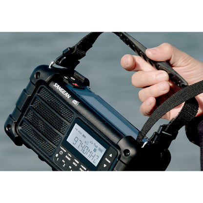 Sangean MMR-99 DAB+ sort hånddrevet radio med solceller, digitalt display viser 97,4 MHz, bærestrop.