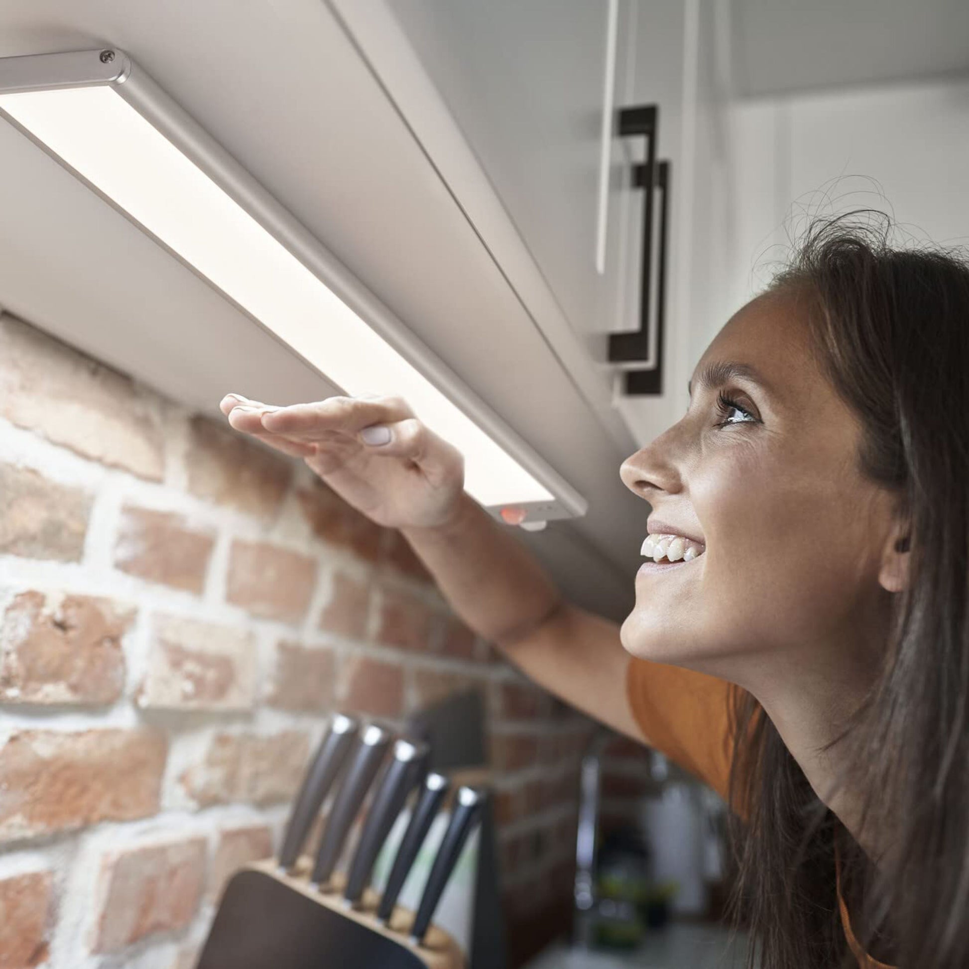 Osram Lineær LED Underskabs belysning med sensor 60cm monteret under skab i køkken med murstensbagvæg og knivblok.