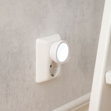 Luxorparts LED natlampe Mini i hvid stikkontakt på lysegrå væg ved siden af hvidt møbel, lyser med blødt hvidt skær.