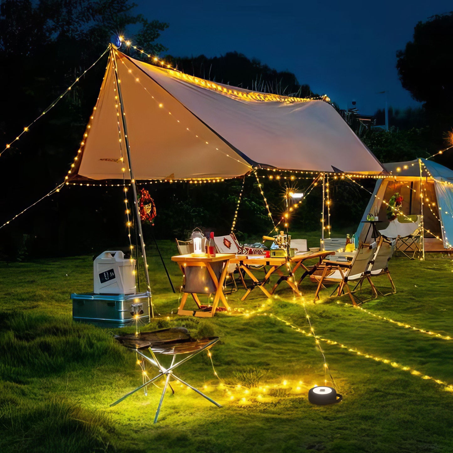 Luxorparts Bærbar campinglygte med LED-lysliste lyser under telt, omgivet af stole, borde og udstyr på græs.