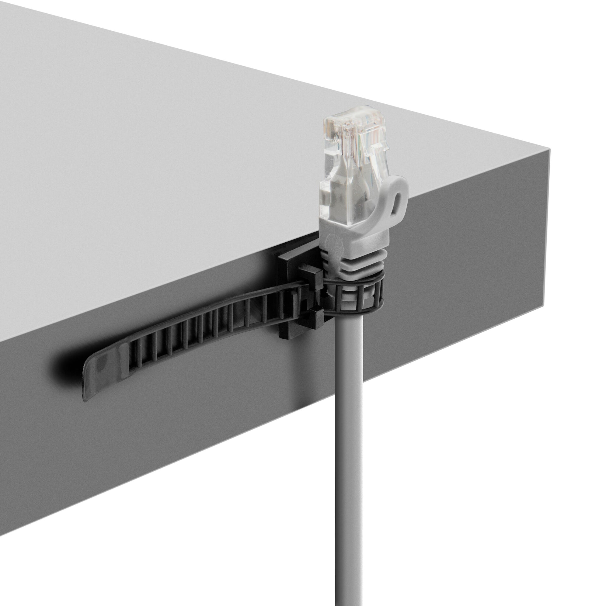 Luxorparts selvklæbende kabelbindere til gråt Ethernet-kabel monteret på kanten af gråt bord for kabelstyring.