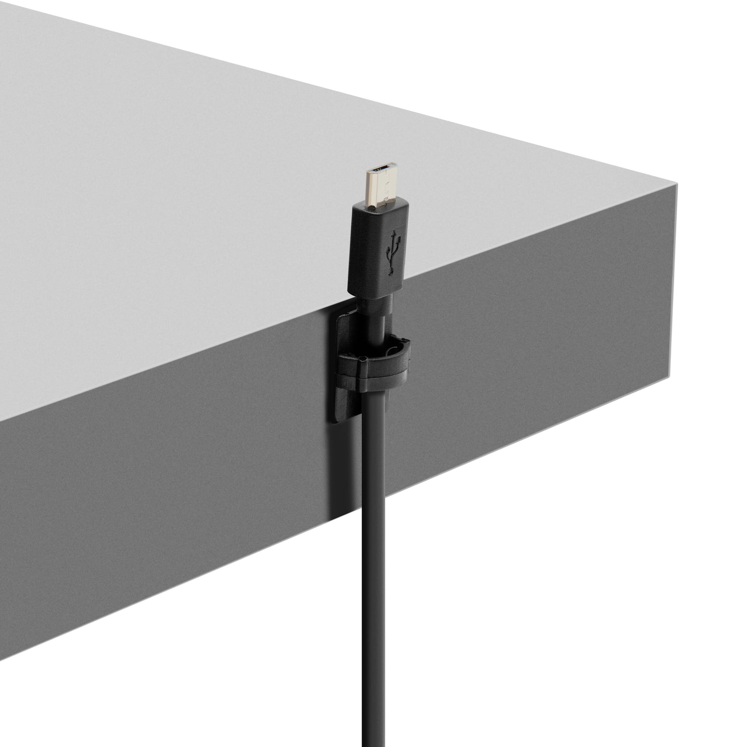 Sort USB-kabel fastgjort til grå bordkant med selvklæbende miniholder, USB-stik peger opad.