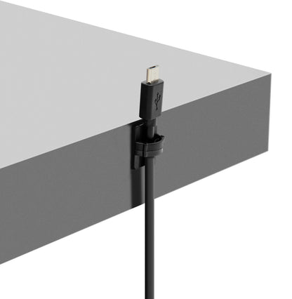 Sort USB-kabel fastgjort til grå bordkant med selvklæbende miniholder, USB-stik peger opad.