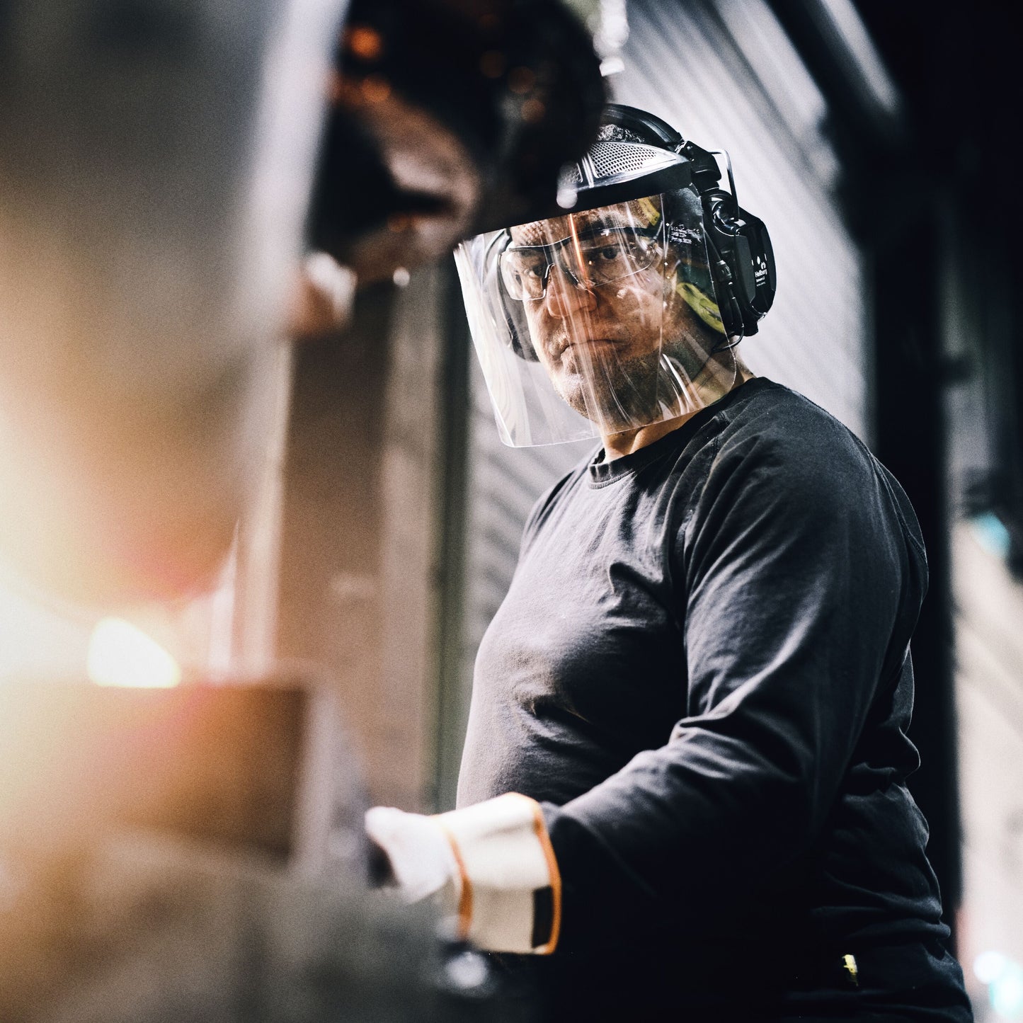 Hellberg Xstream LD høreværn bæres sammen med sikkerhedsbriller, ansigtsskærm og håndsker i industrielt miljø.