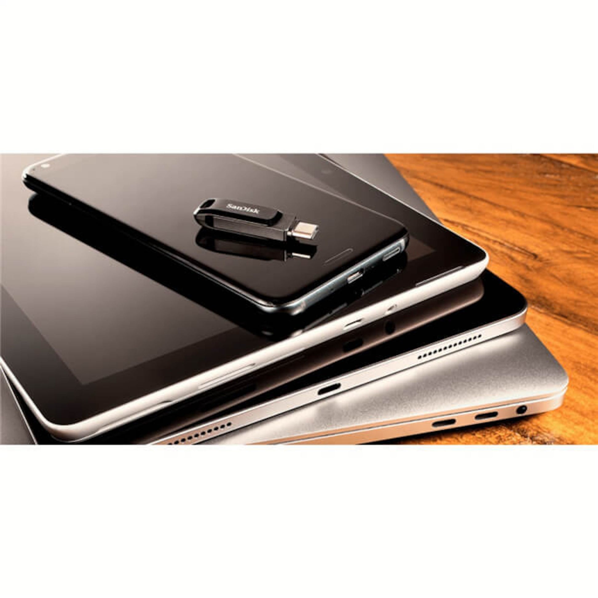 Sandisk Ultra Dual Drive Go USB-stick USB-C 64 GB liggende på smartphone med laptop og tablet i baggrunden.