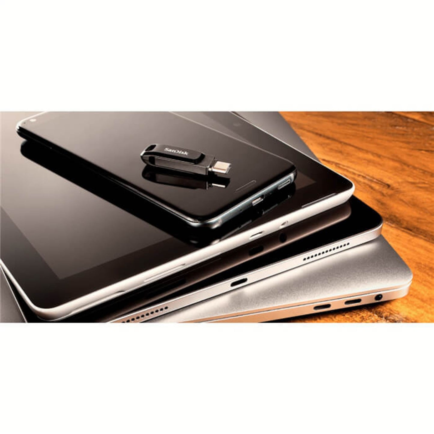 Sandisk Ultra Dual Drive Go USB-nøgle 128 GB med USB-C og Lightning på smartphone ved siden af laptop og tablet.