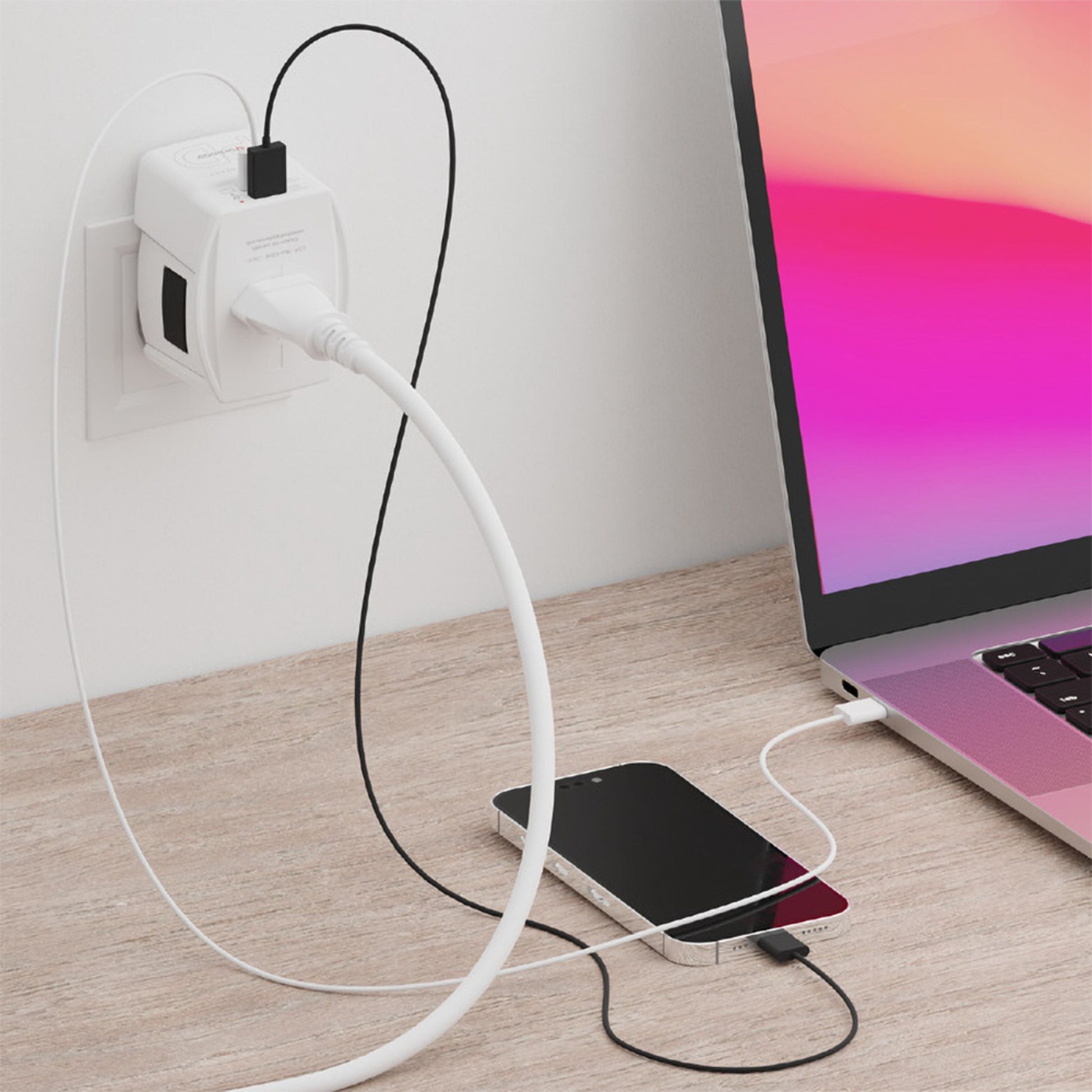 Skross Ujordet Universal rejseadapter med USB PD 65W oplader iPhone og MacBook via kabler på trægulv.