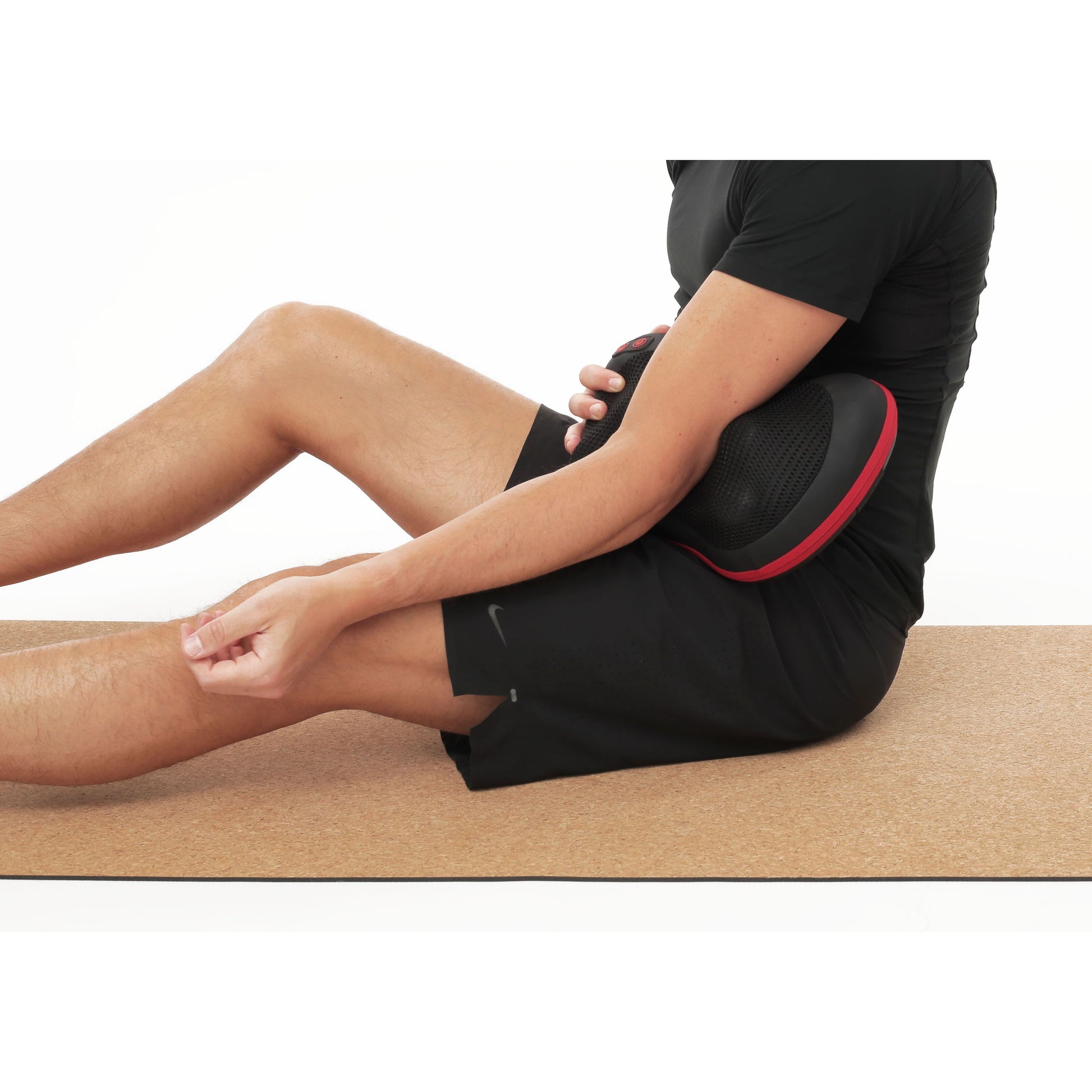 Flowpillow Varmemassagepude med infrarød varme på mave, sort sportstøj, hånd på knæ, anden holder puden.