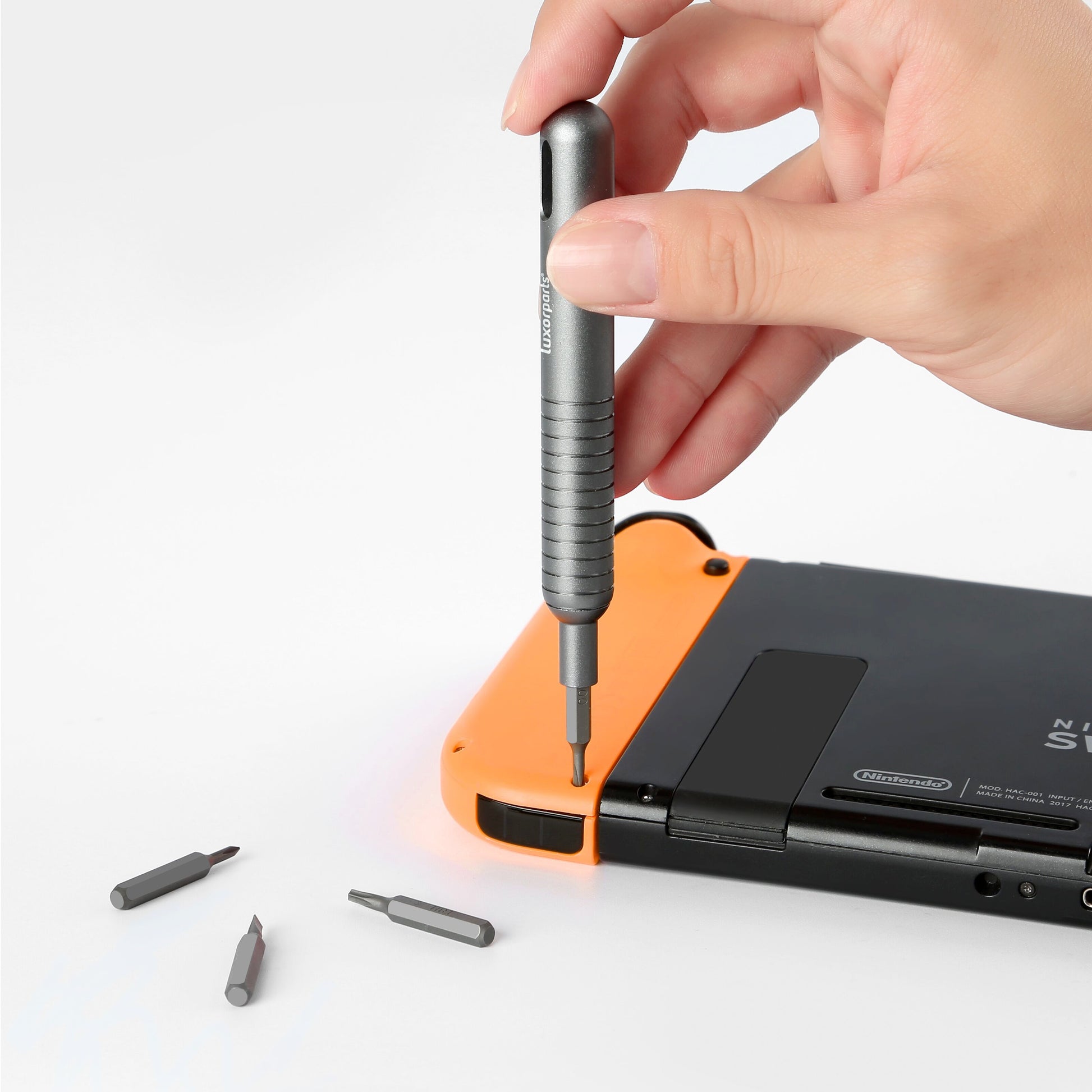 Præcisions skruetrækker fra Skrue sæt 48 dele løsner skrue bagpå orange-sort Nintendo Switch, tre bits ved siden af.