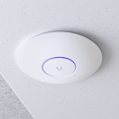 Ubiquiti UniFi U6+ WiFi 6 access point, rund, hvid, blå LED-ring, Ubiquiti-logo, monteret i hvidt loft, PoE 802.11af.