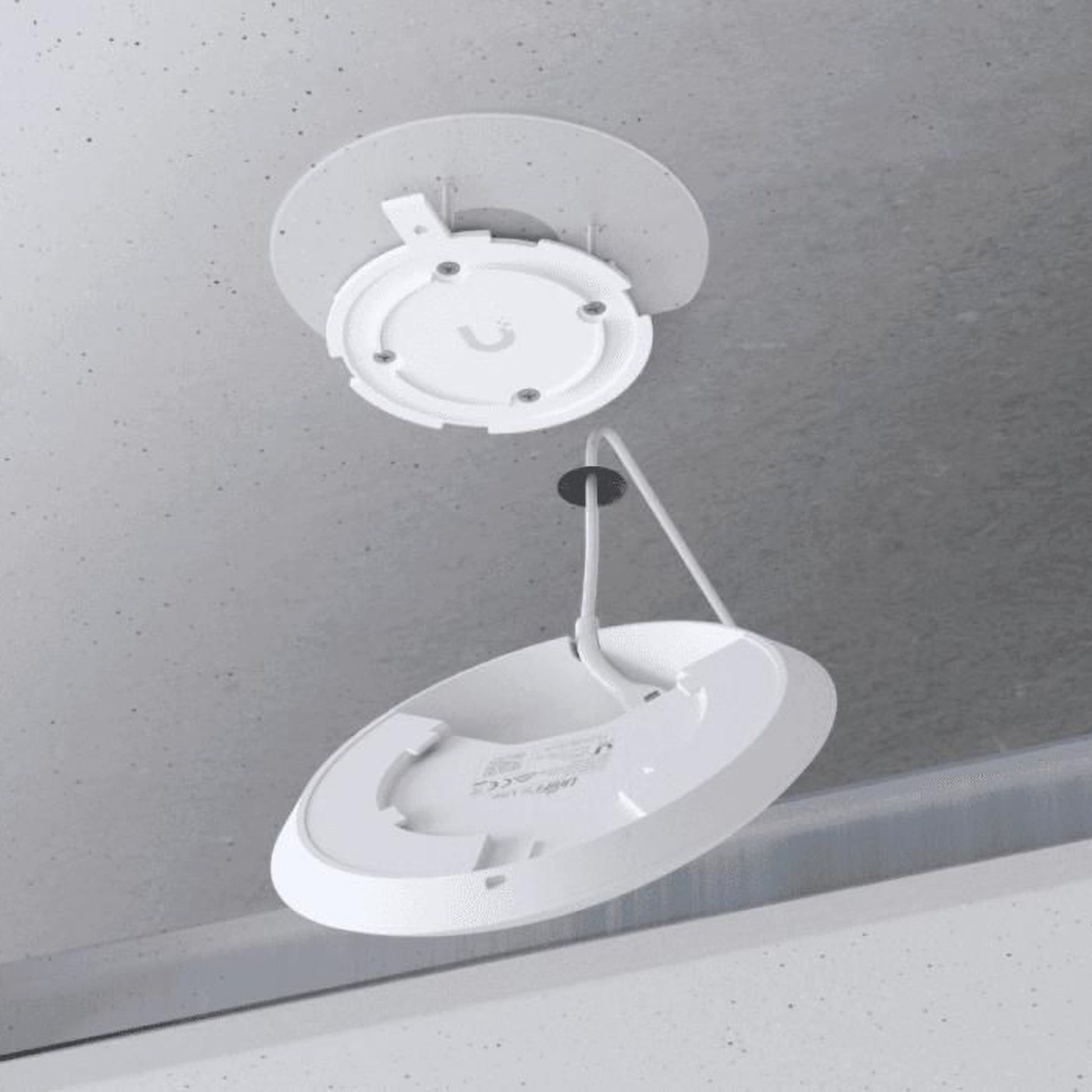 Ubiquiti UniFi U6+ WiFi 6 access point åben fra loftet med synlige ledninger og monteringsbeslag, afkoblet og vippet nedad.