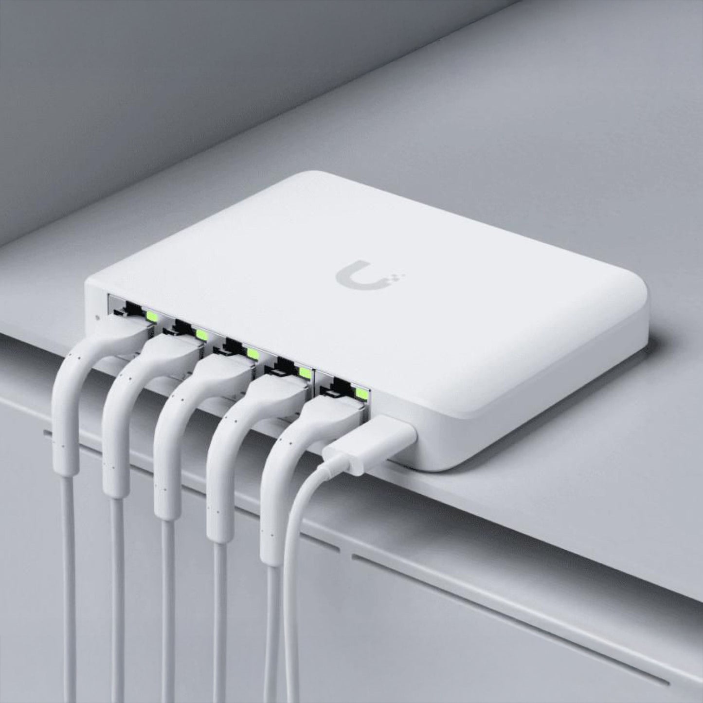 Ubiquiti Switch Flex Mini 2,5G 5P, seks Ethernet-kabler tilsluttet, lys i port-indikatorer, grå overflade.