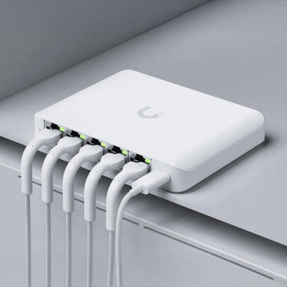 Ubiquiti Switch Flex Mini 2,5G 5P, seks Ethernet-kabler tilsluttet, lys i port-indikatorer, grå overflade.