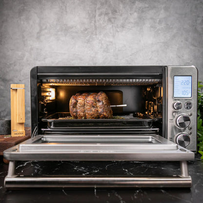 Meater 2 Plus Trådløs grilltermometer i steg i miniovn, display viser temperatur, bambusholder ved siden af.