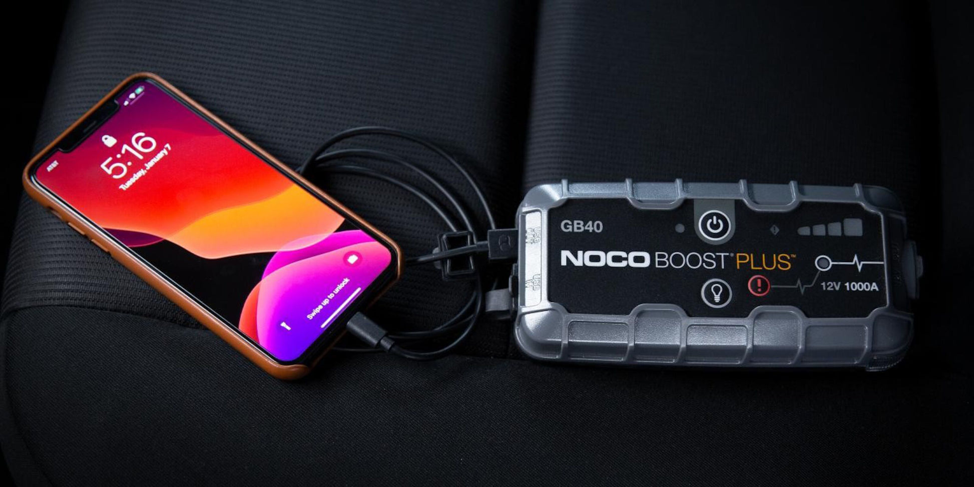 Noco Boost Plus GB40 Start hjælp til bil powerbank oplader smartphone via USB-kabel på bilsæde.