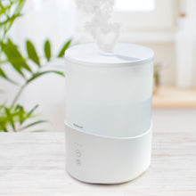 Rubicson luftfugter med timer og stemningsbelysning 2,5 L på lys træoverflade, grøn plante i baggrunden.