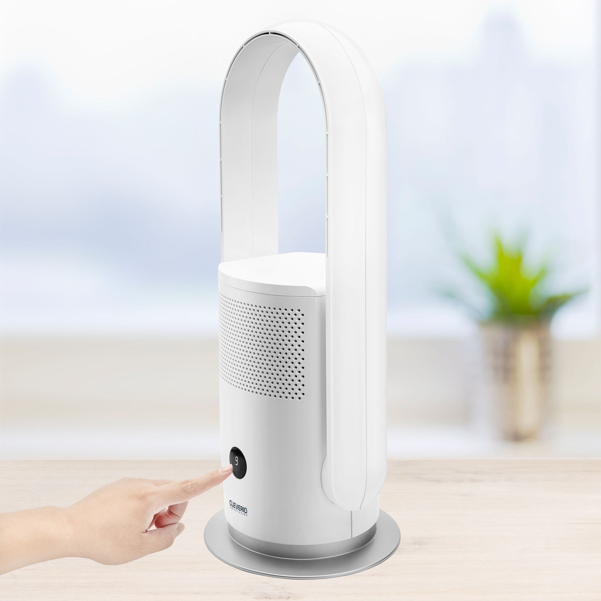 Cleverio AF-F100 gulvventilator med luftfilter, hånd ved tændknap, står på lyst træbord.
