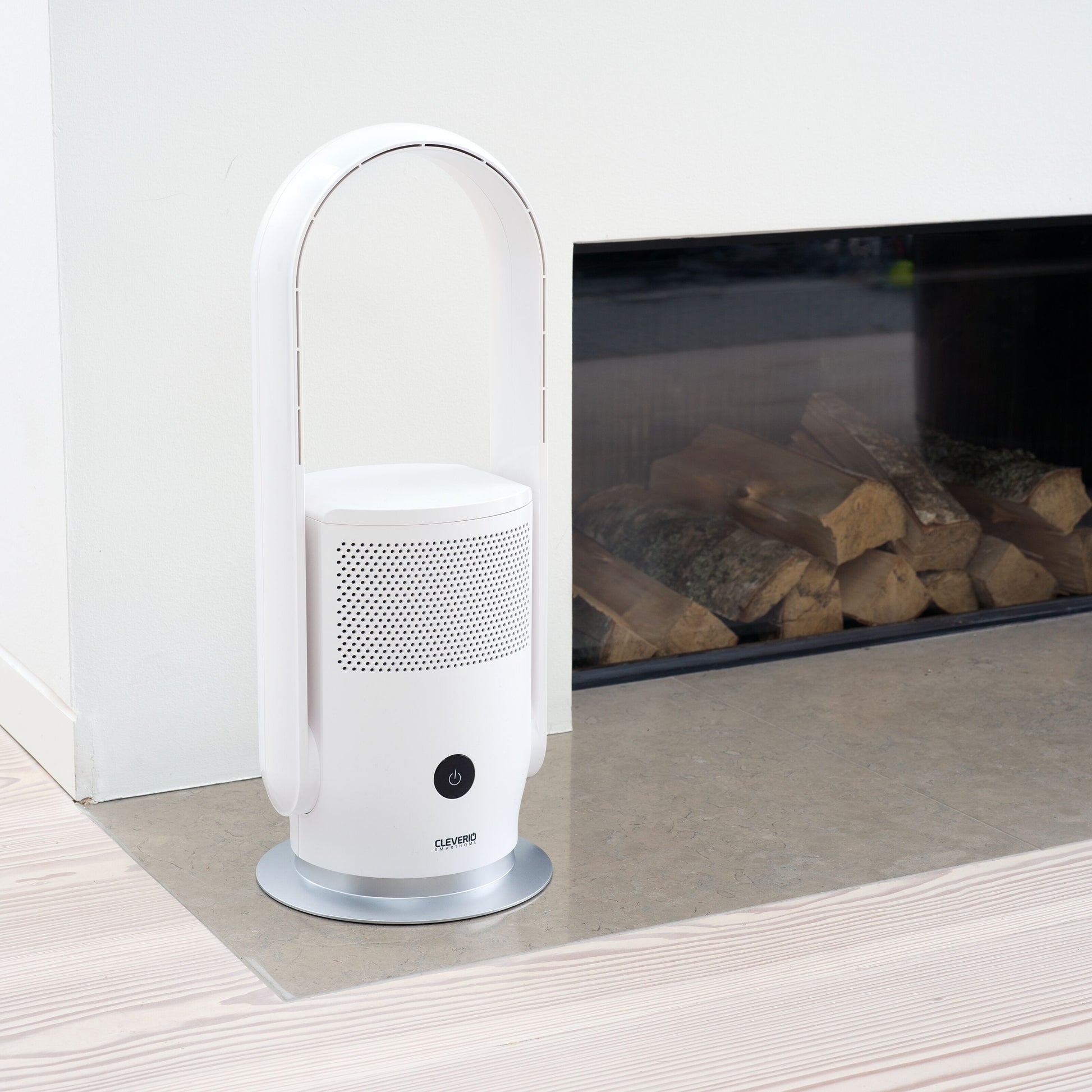 Cleverio AF-F100 gulvventilator med luftfilter på grå stenpejs foran pejs med stablede brændeknuder.