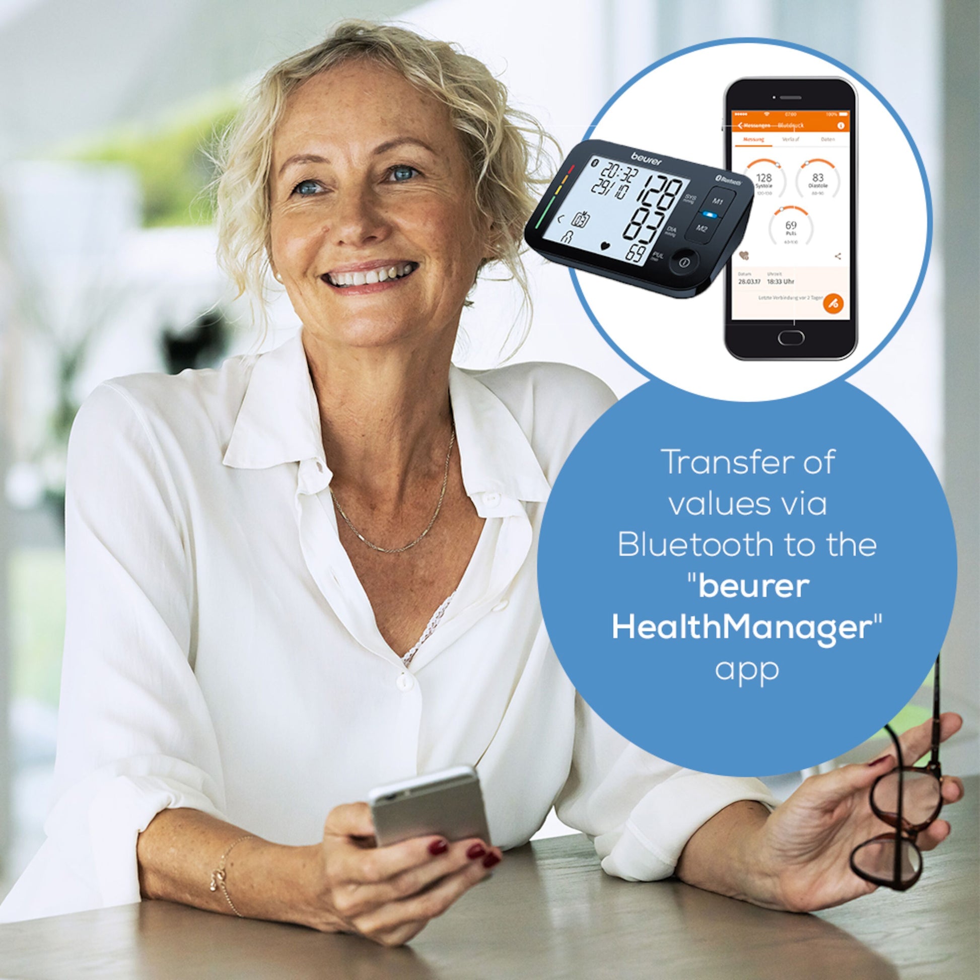 Beurer BM 54 blodtryksmåler til overarm ved siden af smartphone med HealthManager app og synlig Bluetooth dataoverførsel.