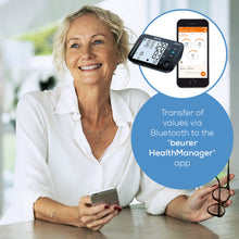 Beurer BM 54 blodtryksmåler til overarm ved siden af smartphone med HealthManager app og synlig Bluetooth dataoverførsel.