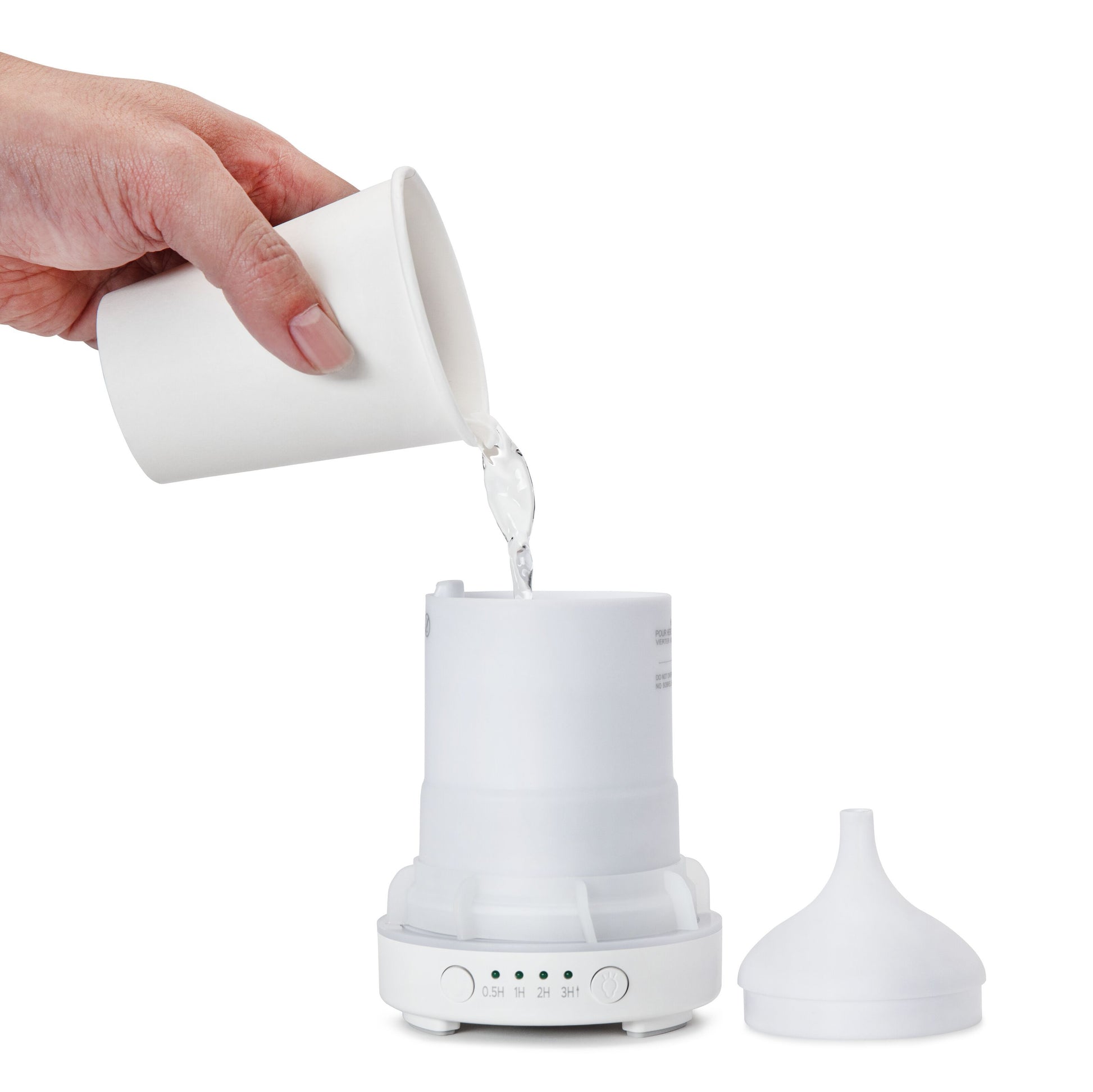 Aromadiffuser med ultralyd, låg ved siden af, vand hældes fra hvid kop i reservoiret, klar til æteriske olier.