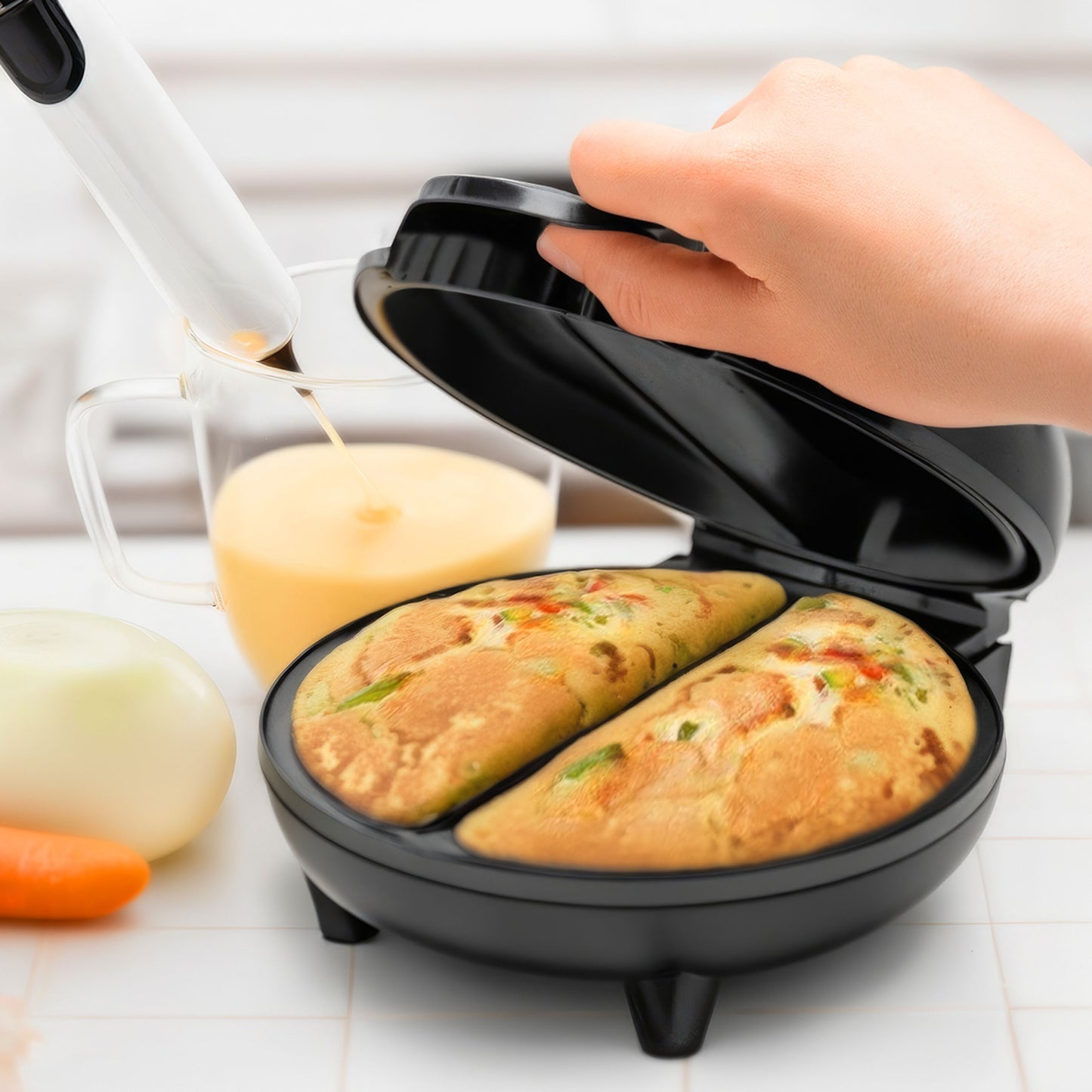 Rubicson omeletjern med non-stick belægning, åben og viser til omeletter, målebæger, piskeris, gulerod og løg i baggrunden.