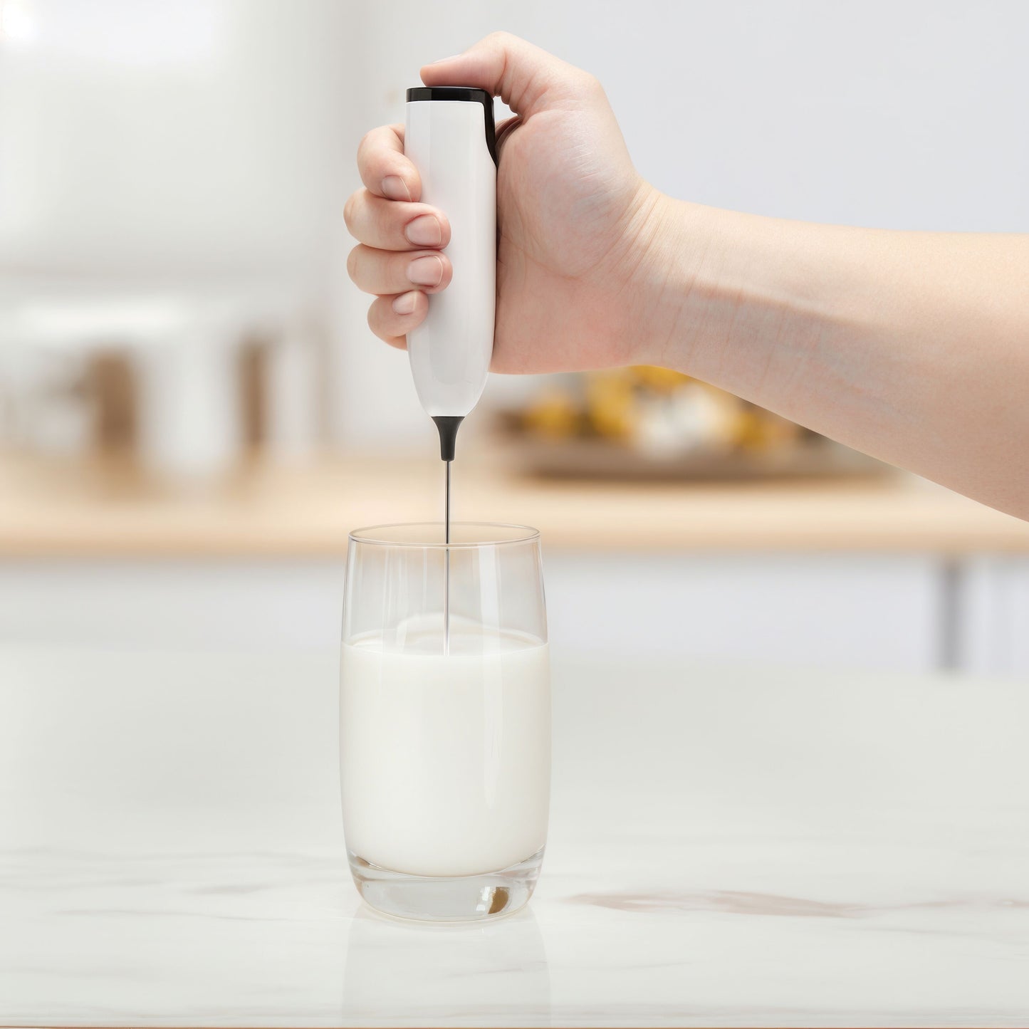 Rubicon batteridrevet mælkeskummer med metalpisker, håndholdt over glas med skummet mælk.