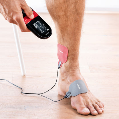 Beurer EM 59 TENS/EMS muskelstimulator med varme med to elektrodepuder placeret på underben og ankel.