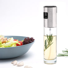 Rubicson sprayflaske til olie ved siden af blå skål med salatblade, tomat, kylling, hvidløgsfed og rosmarin.