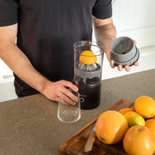 Rubicson Bærbar citruspresser på køkkenbord, appelsin klar til presning, glas og citrusfrugter på træskærebræt.
