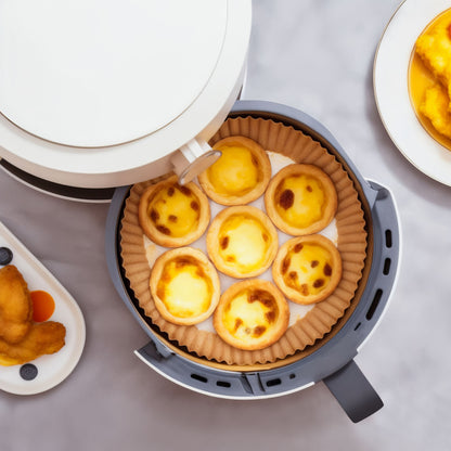 Æggedarretter i åben airfryer med Airfryer papirark 50-pak, nuggets med dip ses ved siden af på marmorbord.