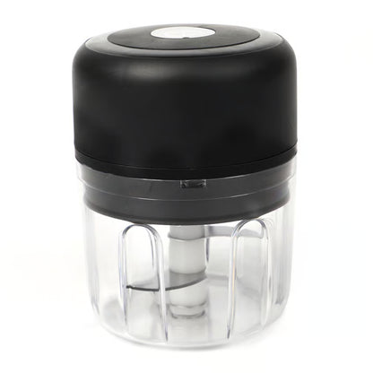Trådløs mini-hakker til grøntsager og frugt, sort/gennemsigtig plast, cylindrisk form, synlig klinge, trykknap på toppen.