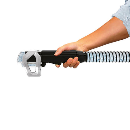 Bissell SpotClean Plus tæppe- og tekstilrenser-slange med klar spiral, sorterer håndtag og person i lyseblå skjorte.