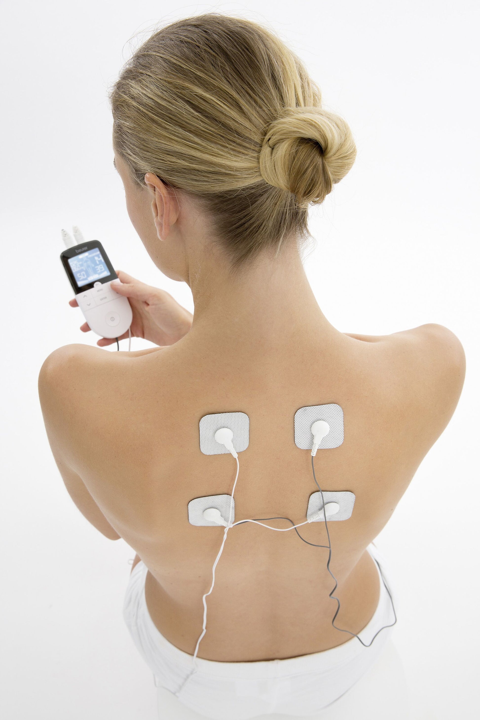 Beurer EM49 TENS muskelstimulator med 4 elektrodeplader placeret på øvre ryg, elektroder forbundet med ledninger.