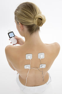 Beurer EM49 TENS muskelstimulator med 4 elektrodeplader placeret på øvre ryg, elektroder forbundet med ledninger.