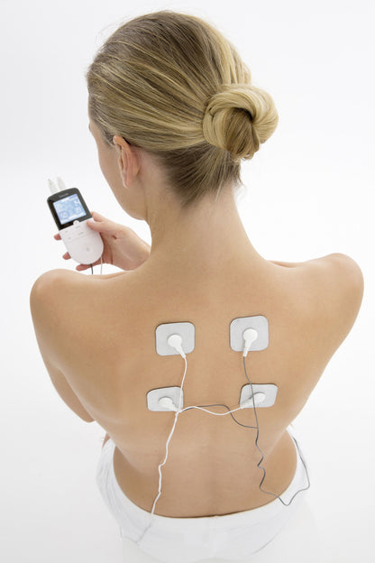 Beurer EM49 TENS muskelstimulator med 4 elektrodeplader placeret på øvre ryg, elektroder forbundet med ledninger.