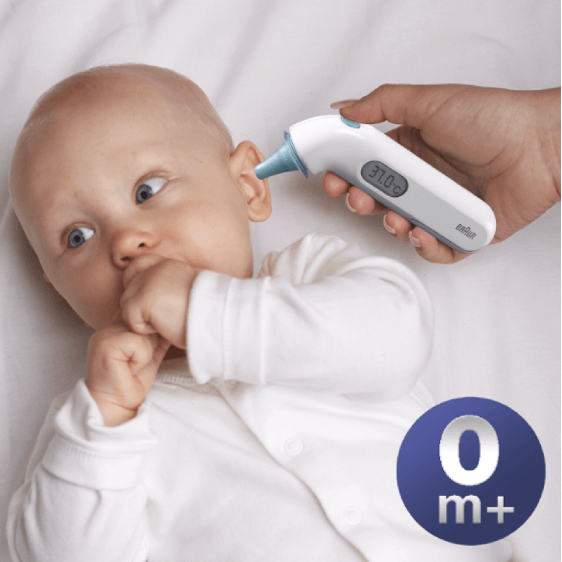 Braun Thermoscan 3 øretermometer bruges til at måle temperatur på baby, "0 m+" ikon synligt i nederste højre hjørne.