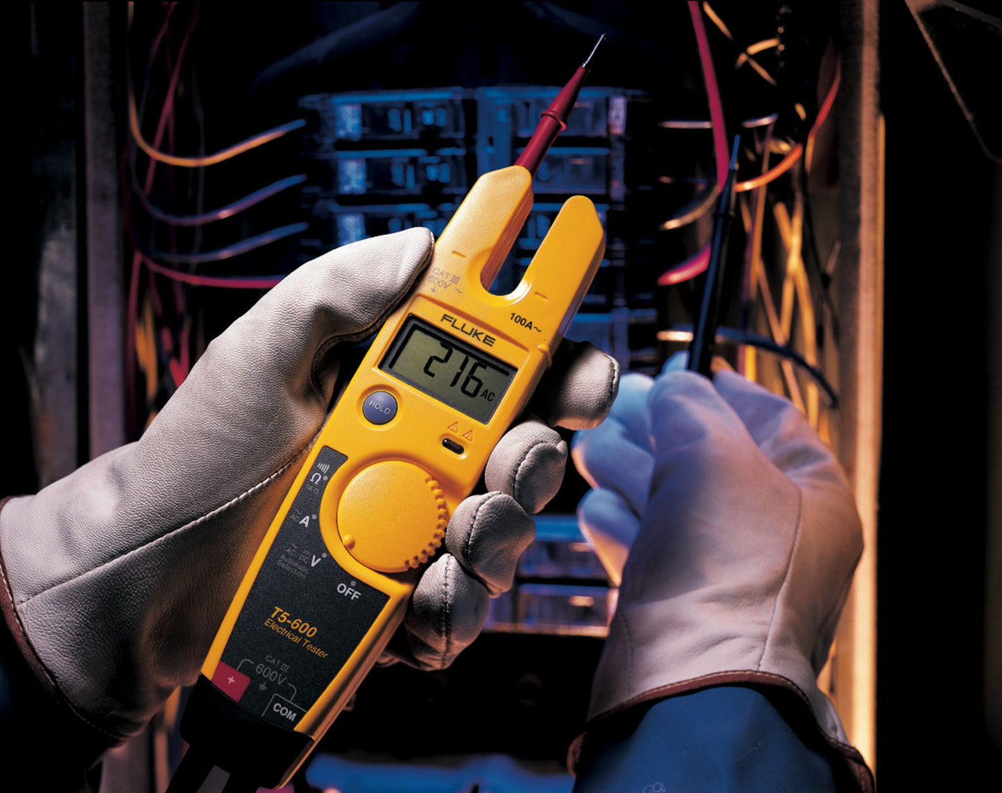 Fluke T5-600 Spændingstester 600 V måler spænding i elpanel med ledninger, person med beskyttelseshåndsker.