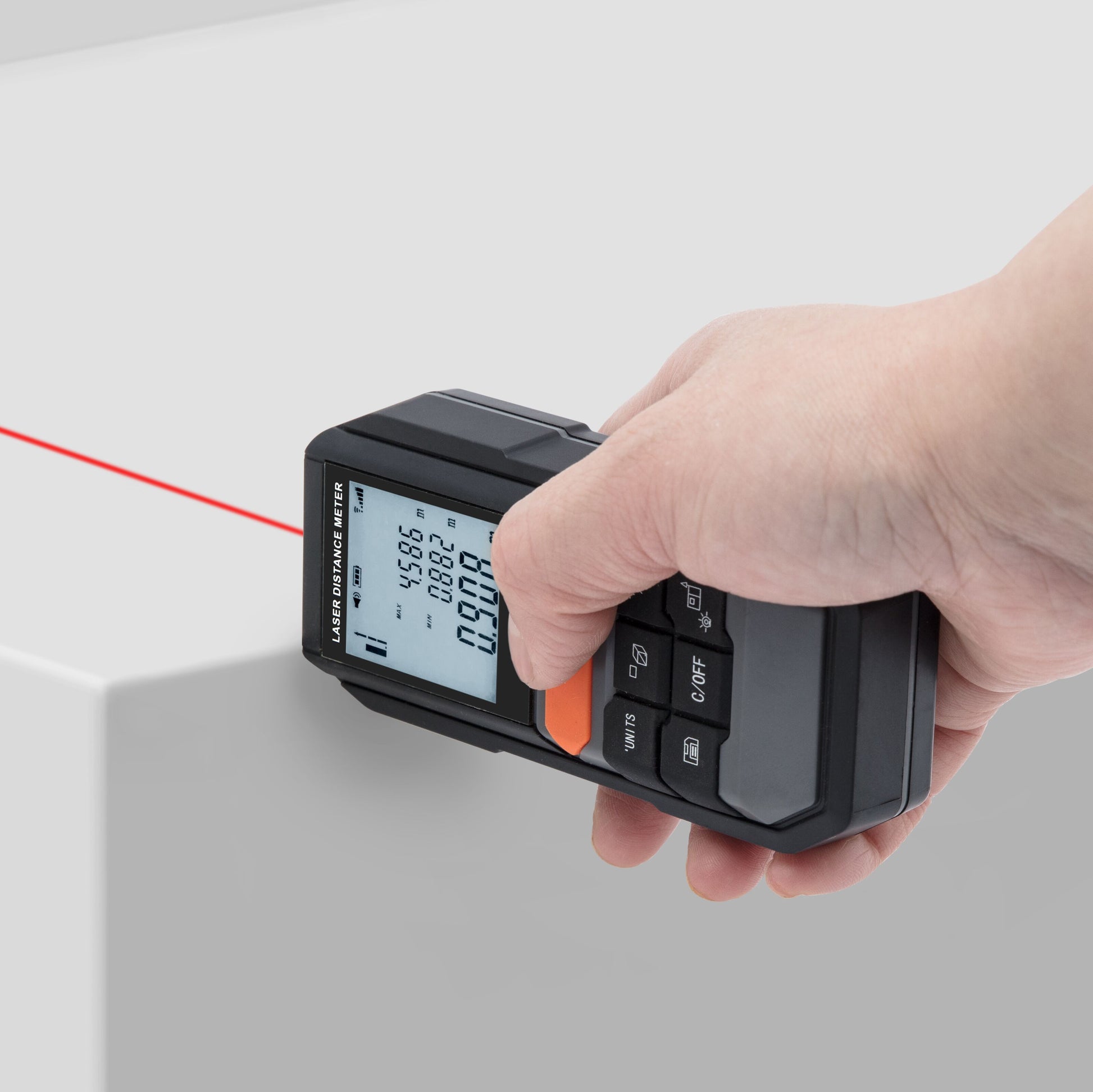 Luxorparts Afstandsmåler med synlig rød laser og digital måling på skærm, holdt i hånd mellem to flader.