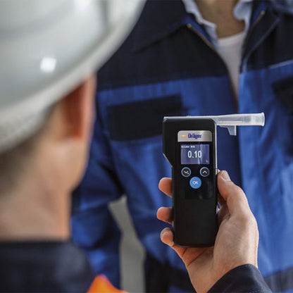 Dräger Alcotest 6000 Alkometer viser 0,10 under brug i arbejdsmiljø af person med sikkerhedshjelm.