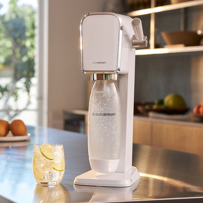 Sodastream sodavandsmaskine på bord ved siden af glas danskvand med lime.