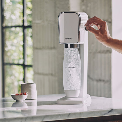 Sodastream sodavandsmaskine hånd drejer knap og laver danskvand i gennemsigtig flaske.