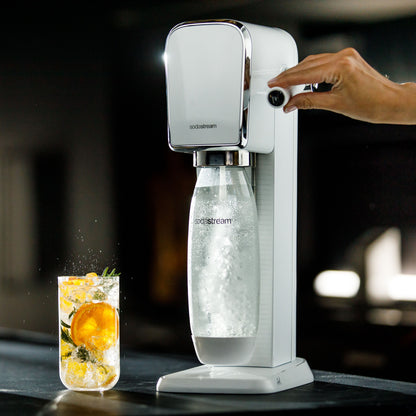 Sodastream Sodavandsmaskine karbonerer vand i klar flaske, citrusdrik med appelsin, mynte og er ved siden af.