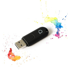 Conbee II Zigbee-controller USB sort med sølv stik, omgivet af farverige malerstænk.