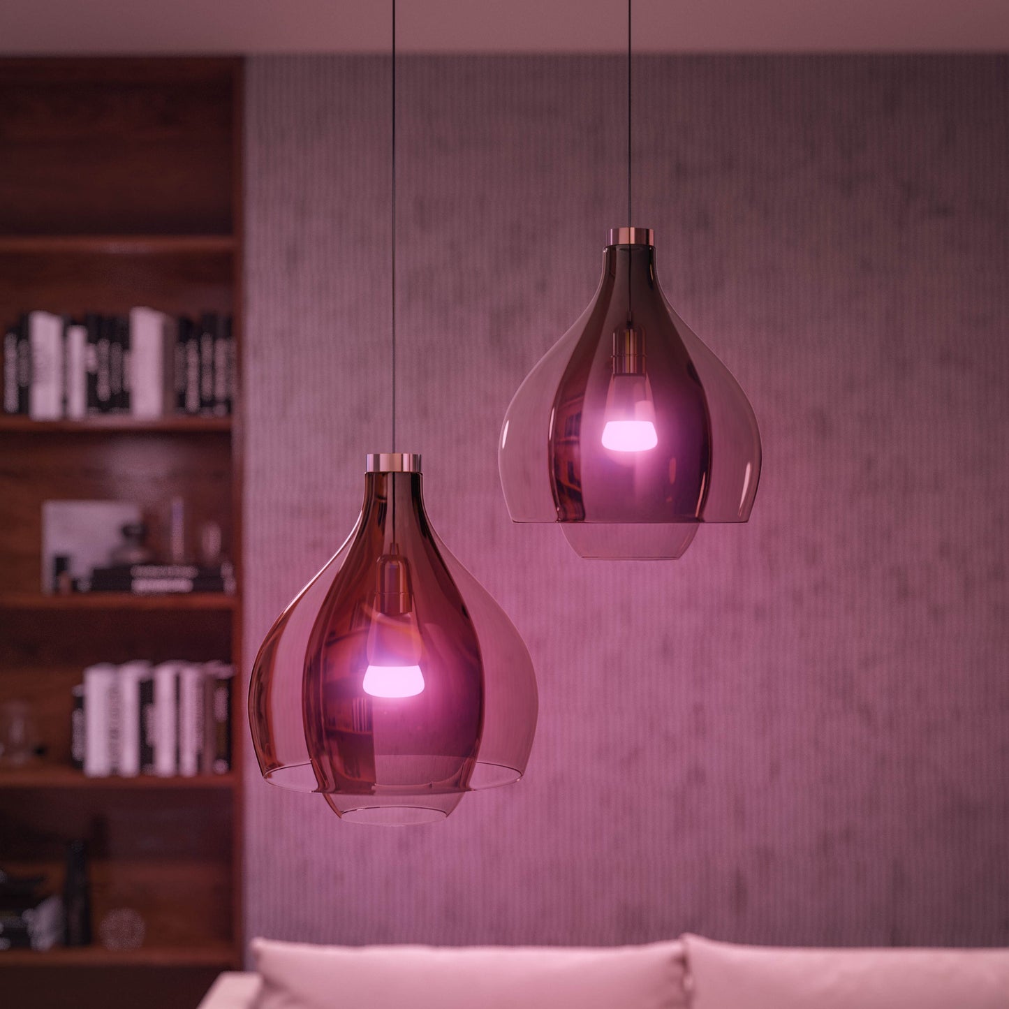 Philips Hue Color Ambiance Startpakke Smarte LED-pærer 2-pakke i lilla glaspendler over hvid sofa, reol og væg ses.