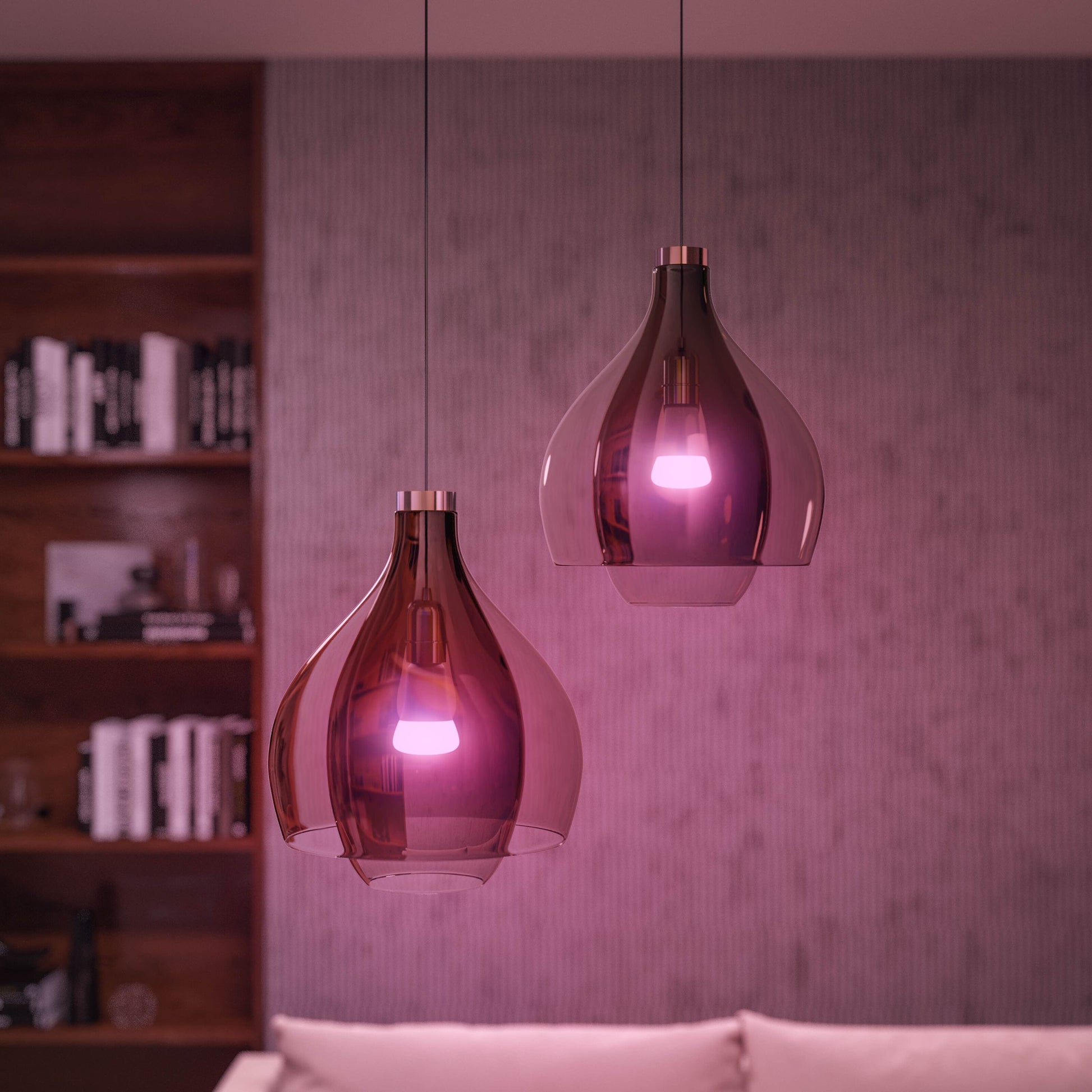 Philips Hue Color Ambiance Startpakke Smarte LED-pærer 2-pakke i lilla glaspendler over hvid sofa, reol og væg ses.