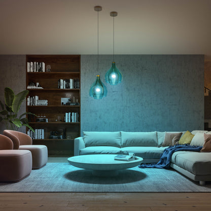 Philips Hue Color Ambiance Startpakke smarte LED-pærer i to blågrønne pendellamper over sofagruppe og bord.