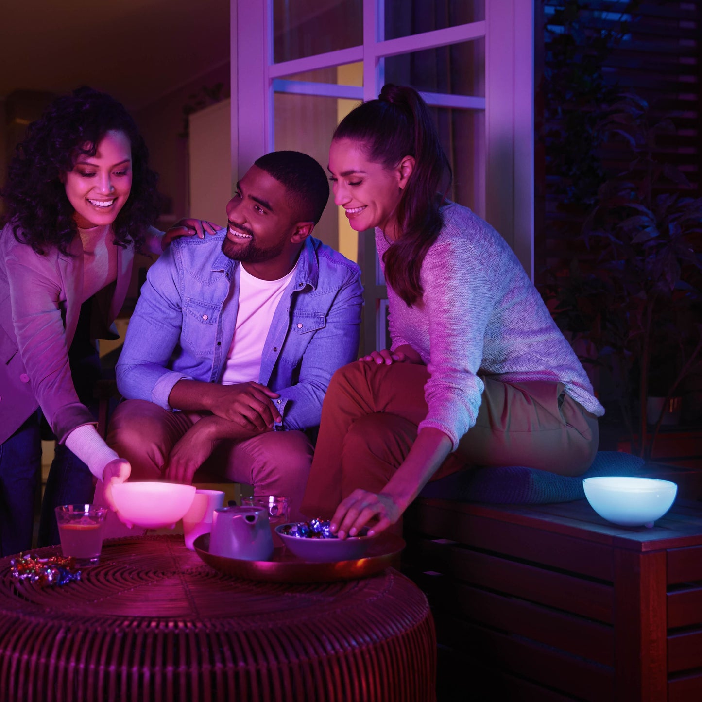 Philips Hue Go bærbar bordlampe med Bluetooth på bord i brug, nat, blødt lys lyser op snacks og personer.