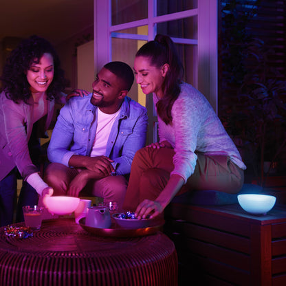 Philips Hue Go bærbar bordlampe med Bluetooth på bord i brug, nat, blødt lys lyser op snacks og personer.