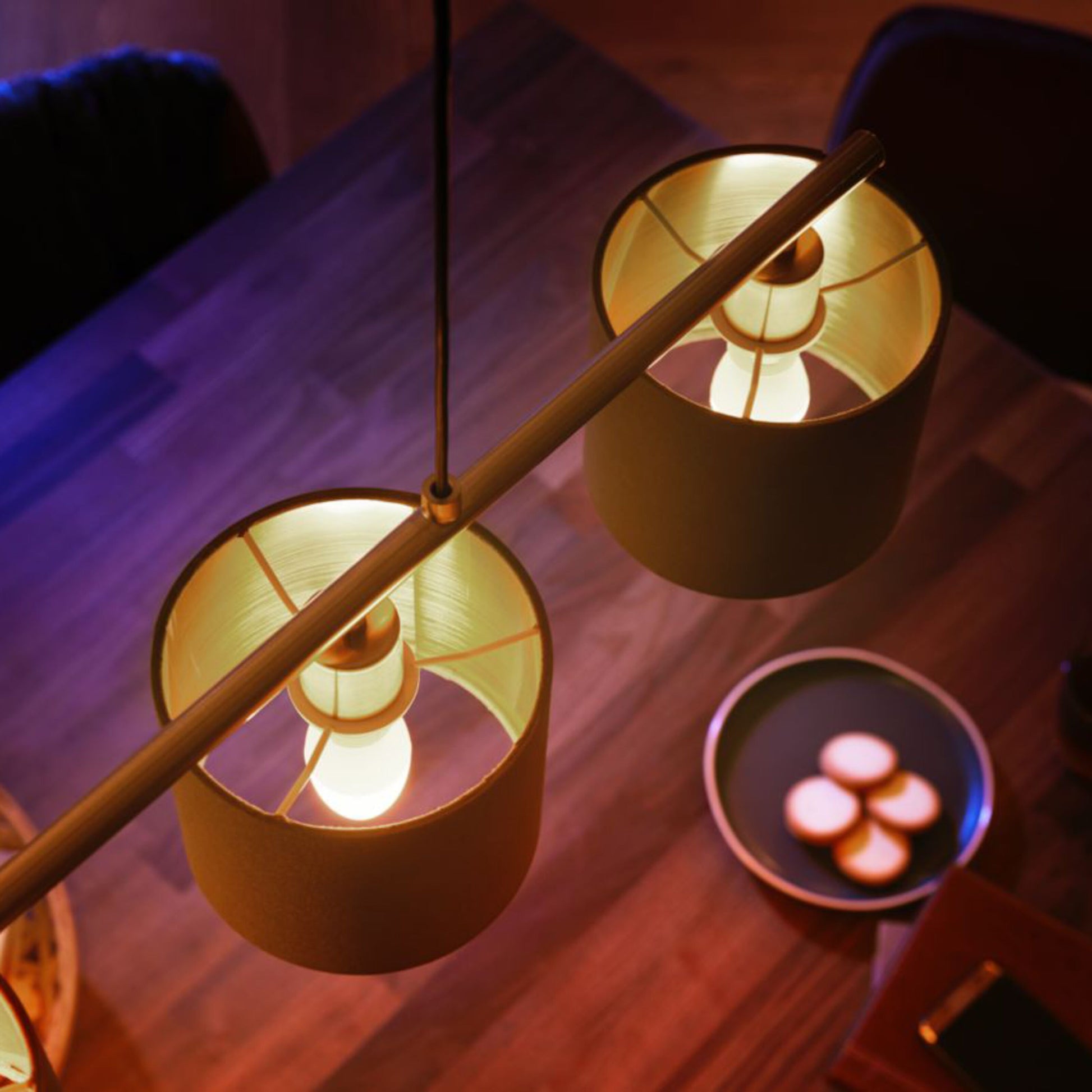 Philips Hue Hvid Smart LED-pære E14 470 lm 2-pak dæmpbart varmt lys over træbord med tallerken og småkager.